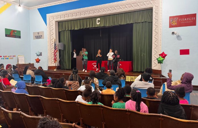  Group of girls performing step routine in front of auditorium full of spectators.